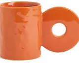 En orange mugg med ett cirkulärt handtag. Perfekt för ditt keramik hemma utan ugn-projekt.