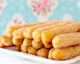 Montón de churros dorados espolvoreados con azúcar, perfectos para aprender como hacer churros caseros.