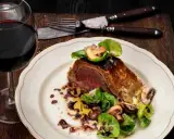 En saftig wellington biff serveras med svamp och grönsaker, ackompanjerad av ett glas rött vin.