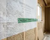 Gros plan sur une membrane hygrovariable Vario Xtrasa Safe, fixée sur une structure en bois. Un ruban vert Airseal Siga Rissan 60 est appliqué.