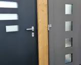 Dwie nowoczesne drzwi wejściowe, ciemnoszare i szare, z przeszkleniami. Ocieplenie drzwi wejściowych to klucz do komfortu.