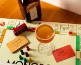 Ein Sidecar Cocktail steht auf einem Monopoly-Spielbrett neben einer Flasche Cointreau.