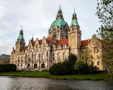 Imponujący Nowy Ratusz w Hanowerze, jedna z głównych atrakcji miasta, z zieloną kopułą i wieżami, nad jeziorem.