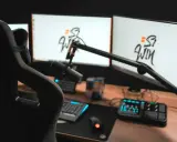 Setup streamer avec fauteuil, deux écrans affichant un logo, micro sur bras articulé, clavier, souris et console de mixage.