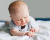 Ein süßes Baby liegt auf dem Bauch, die Augen geschlossen, als würde es die Welt entdecken. Ein Zeichen des baby 6 wochen wachstumsschub.