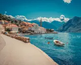 Sommerurlaub am Meer: malerische Küstenstadt mit roten Dächern, blauer Bucht und Bergen im Hintergrund.