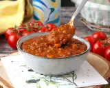 En skål med mustig bolognese, perfekt för ett gott bolognese recept. Färska tomater i bakgrunden.