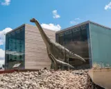 Dos dinosaurios gigantes, como los que verían los niños en la cuenca, posan frente a edificios modernos.