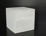 Ein Würfel aus hellem Beton C30/37 steht auf schwarzem Untergrund.