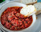 Schüssel mit würzigem Acili Ezme, einem scharfen türkischen Dip aus Tomaten und Paprika, serviert mit frischem Brot.