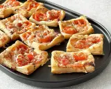 Pizzerinki z ciasta francuskiego z pomidorkami i serem, idealne na szybką przekąskę.