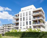 Immeubles modernes avec balcons fleuris, sous un ciel bleu. Un projet immobilier qui pourrait bénéficier de la loi Borloo pour son accessibilité.