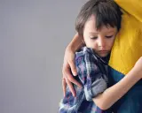 Niño de 6 años abraza a su madre con apego excesivo, buscando consuelo en su abrazo protector.