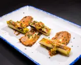 Puerros a baja temperatura, tiernos y dorados, servidos con una sabrosa salsa y granos de mostaza.