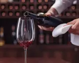 Un calice di vino rosso viene versato da una bottiglia, un momento perfetto per un tour enogastronomico Toscana.