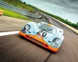 Ein ikonischer Porsche Rennwagen aus den 80ern, der Gulf-Porsche 917, rast auf einer Rennstrecke.