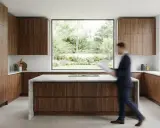 Cuisine en U de petite surface, 5m2, avec îlot central et grandes fenêtres offrant une vue sur le jardin. Meubles en bois de noyer.