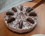 Pyszny sernik oreo, ozdobiony ciasteczkami i posypką, czeka na pokrojenie.