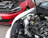 Dos Volkswagen Golf 7 GTI, uno rojo y otro blanco, con capós abiertos mostrando sus motores.