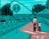 Ojciec i syn na rowerach jadą ścieżką rowerową. Obowiązują przepisy dla rowerzystów, w tym ograniczenie prędkości do 60 km/h.