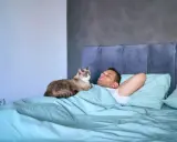 Kot śpi na człowieku, co oznacza głębokie zaufanie i poczucie bezpieczeństwa. Zwierzę czuje się komfortowo i kochane.
