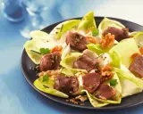 Salade de gésiers savoureuse avec endives croquantes, noix et persil frais, assaisonnée d'une vinaigrette aux graines.