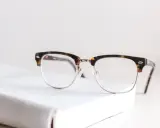 Okulary w stylu retro leżą na białej książce. Zastanawiasz się, od ilu dioptrii trzeba nosić okulary?