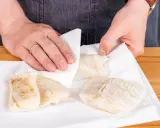 Hände tupfen Steinbeißer Fischfilets auf Küchenpapier trocken, bereit für die Zubereitung.