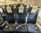 Puste, ciemne fotele w samolocie Enter Air z pasami bezpieczeństwa.