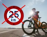 Chcesz wiedzieć, jak zdjąć ogranicznik prędkości w rowerze elektrycznym? Znak zakazu 25 km/h przekreślony, obok rowerzysta z rowerem elektrycznym.