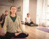 Mujeres meditando en clase de yoga. Una de ellas, en primer plano, parece estar en el **primer trimestre de embarazo**, buscando calma y conexión.