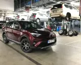 Czerwona Toyota RAV4 w serwisie. W tle inne auta na podnośnikach. Zastanawiasz się nad toyota trzeci przegląd gwarancyjny cena?