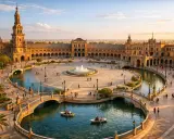 Zachód słońca nad Plaza de España w Sewilli. Ludzie pływają łódkami po kanale, a w tle widać wspaniałą architekturę. To piękne sevilla miasto.