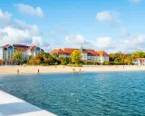 Piękna plaża z hotelami i spacerującymi ludźmi, idealne miejsce na weekendowy relaks nad morzem.