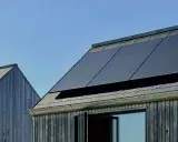 Mörka träfasader möter tak med solpaneler. En modern, hållbar design som fångar solens energi, nästan som en denim solar-dröm.