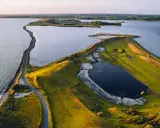 Grönskande landskap med en slingrande väg längs kusten i Danmark. En vy som från ett utkikstorn Danmark, med vatten och fält.