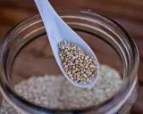 Eine Löffelspitze voller Quinoa, dem gesunden Korn, das in einem Glas aufbewahrt wird.