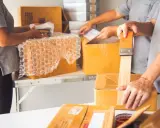 Kurierzy sprawnie pakują paczki, zabezpieczając zawartość folią bąbelkową i taśmą klejącą.