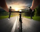 Rowerzysta w rękawiczkach pędzi po asfalcie. Słońce zachodzi, a krajobraz rozmywa się w tle. Ile czasu zajmie mu przejechanie 100 km rowerem?