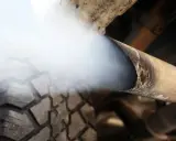 Biały dym z wydechu diesel wydobywa się z rury, zasłaniając fragment opony.