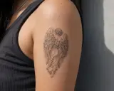 Tatouage d'ange aux ailes déployées, évoquant la protection et la spiritualité. L'auréole ange signification est ici représentée par la grâce de l'œuvre.