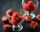 Jak zrobić sorbet truskawkowy? Pyszny, orzeźwiający deser w pucharkach, otoczony świeżymi truskawkami. Idealny na upalne dni.
