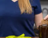 Kobieta zanurza torebkę herbaty w kubku, obok leży miarka. Czy nerki można wygrzewać?