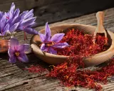 Safranblüten und getrocknete Safranfäden in einer Holzschale. Die Safran Wirkung auf den Schlaf ist legendär.
