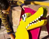 Un niño interactúa con un cocodrilo amarillo de utilería, parte de un espectáculo de teatro infantil en Málaga.