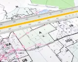 Plan zagospodarowania przestrzennego z naniesionymi strefami i podziałami. Linijka geodezyjna pomaga w precyzyjnych pomiarach.
