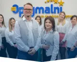 Zespół uśmiechniętych doradców podatkowych w białych koszulach przed logo firmy.