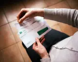 Dłonie trzymają kopertę ZUS. W środku decyzja o waloryzacji emerytury, być może zapowiedź trzynastej emerytury.