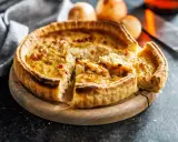 Une part de quiche lorraine, une des spécialités lorraines, sur une planche en bois.