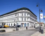 Elegancki, biały budynek w centrum Warszawy, być może najdroższy hotel w Warszawie. Słoneczny dzień, ruch uliczny.